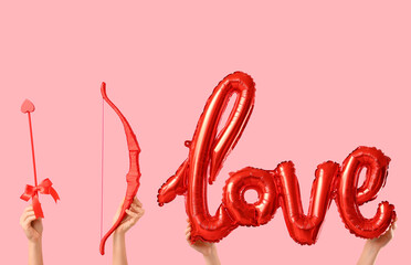 Naklejka premium Female hands with cupid's bow, arrow and balloon in shape of word LOVE on color background. Valentine's Day celebration