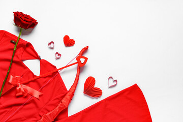 Naklejka premium Composition with red dress, cupid's bow and rose flower on light background. Valentine's Day celebration