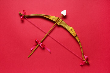 Naklejka premium Golden cupid's bow with arrow on red background. Valentine's Day celebration
