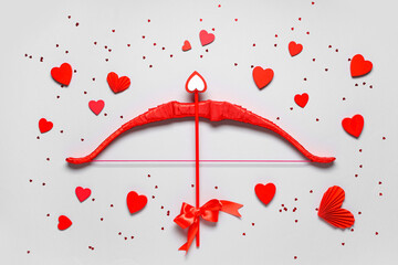 Naklejka premium Composition with red cupid's bow and paper hearts on grey background. Valentine's Day celebration