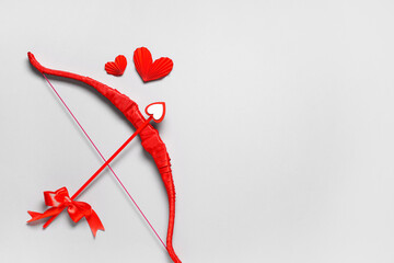 Naklejka premium Red cupid's bow and paper hearts on grey background. Valentine's Day celebration