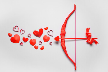 Naklejka premium Composition with cupid's bow and different paper hearts on grey background. Valentine's Day celebration