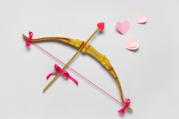 Naklejka premium Composition with cupid's bow and paper hearts on grey background. Valentine's Day celebration