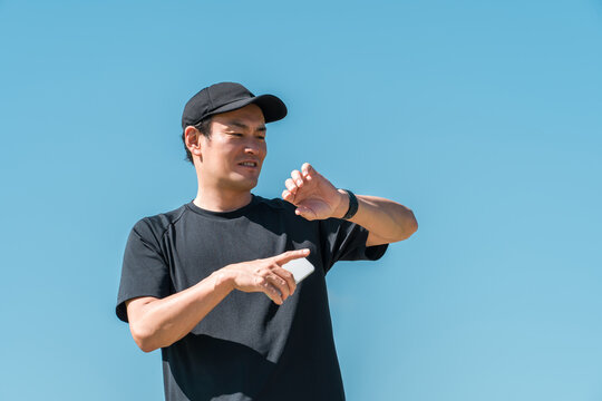A middle-aged man in sportswear using a smartwatch, pedometer, and pedometer to manage his health and wellness