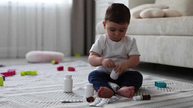 Child safety at home. Little boy playing with pills on floor indoors