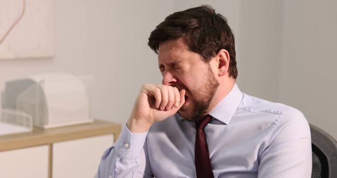 Unhappy businessman feeling fatigue at wooden table in office. Camera moving forward
