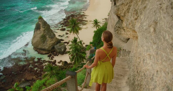 Woman looking at ocean from steep cliff side path at Diamond Beach Bali Indonesia