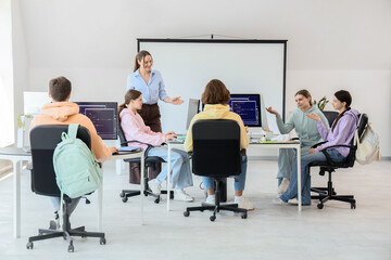 Teenage students with teacher studying at school computer lab