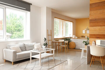 Fototapeta premium Interior of light room with table and comfortable sofa near window