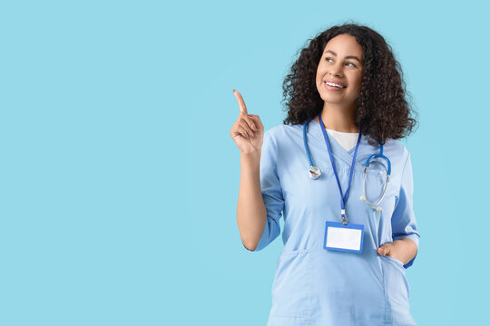 Female African-American medical student pointing at something on blue background