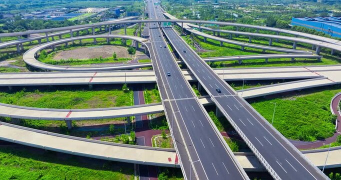 Aerial shot of a complex highway interchange with cars driving on multiple levels in a modern city during a bright sunny day.