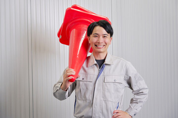 三角コーンを持つ作業員　倉庫　ポートレート　カメラ目線