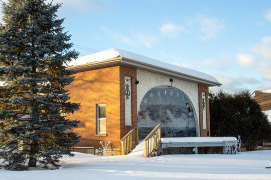 A snow-covered outdoor municipal theatre and stage in a city park during a sunny winter day