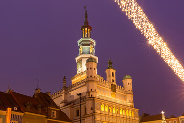 Naklejka premium Historic Poznan town hall glowing with warm lights against the evening sky, decorated for the winter season.