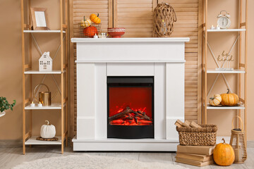 Obraz premium Interior of stylish room with shelving units and autumn decorations on modern fireplace near beige wall