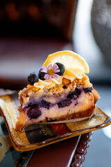 A beautiful blueberry cheesecake topped with lemonade is served on a plate, with a cafe as the backdrop.