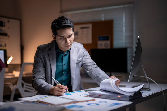 Asian businessman working extra hours preparing office paperwork