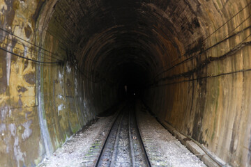 Naklejka premium Dark mysterious railway tunnel with train tracks leading into unknown blackness. Scary underground passage creating path on journey filled with suspense and fear