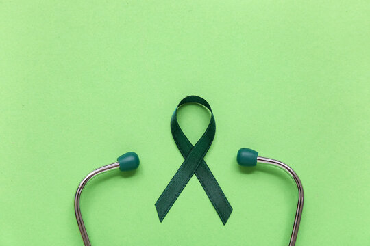 Satin green ribbon and stethoscope on color background. National cerebral palsy awareness month.