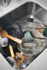 Dishes and utensils piled in a kitchen sink after cooking