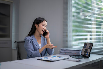 Obraz premium Asian businesswoman talking on phone and analyzing charts in office