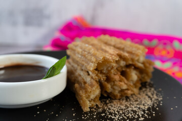 Churros on a plate, with chocolate to accompany them.