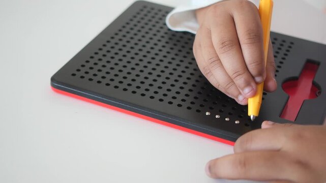 Child Engaging with Magnetic Dot Drawing Board for Creative Play