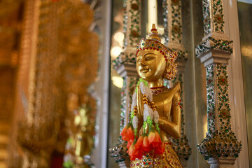 Fototapeta premium Serene golden statue of Buddha with gentle smile. Beautiful sculpture and art inside traditional temple in Asia. symbol of faith, peace, and religion