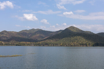 Fototapeta premium Serene and scenic landscape of calm lake and vast mountain range under blue sky. peaceful outdoor nature view evokes sense of tranquility and adventure