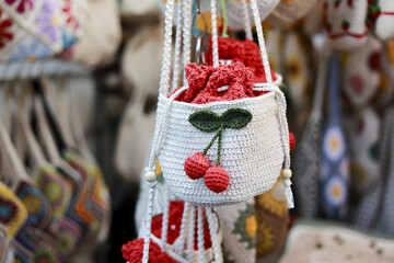 Charming handmade white crochet hanging basket with red cherry decoration. cute craft item for sale at market, perfect for home decor or as unique plant holder