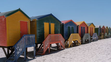 Naklejka premium Colorful beach huts line the sandy shores of Muizenberg in Cape Town, South Africa