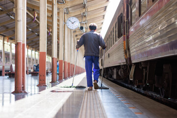 Fototapeta premium Worker mopping train station platform during daytime
