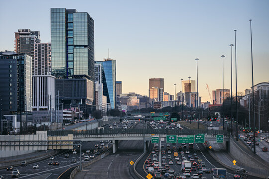 View of the Downtown Atlanta Skyline Cityscape showing several prominent buildings, highways, cars, and hotels after sunrise.