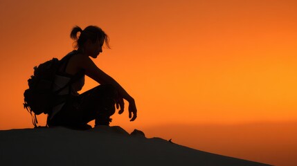 A silhouette of a person sitting on a dune during a sunset, creating a scene of contemplation and peace