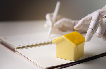 Robotic Hand Writing Notes Near Small House Model for AI Real Estate Concept