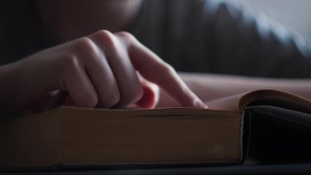 Child reading a big book, close-up finger following lines on page, learning to read concept