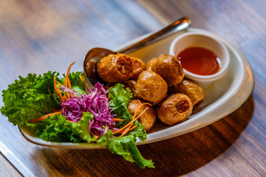 Deep fried crab meat roll serving with chillies sauce on wooden table