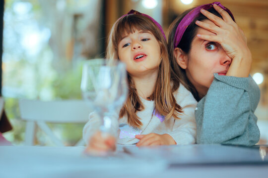 Mom Exasperated by Naughty Behavior of her Daughter in a Restaurant. Lenient mom attempts to manage her kid being disruptive during a formal dinner 