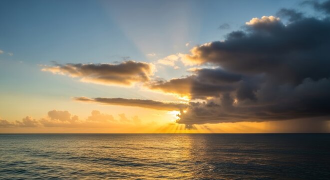 Sunset over calm ocean with dramatic storm clouds and sun rays on horizon