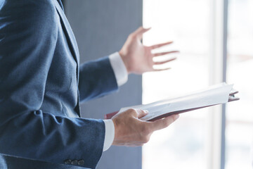 会議で紙資料を見てプレゼンテーションする男性ビジネスマン