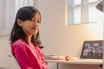 An Indonesian female student studying online from home using tablet computer