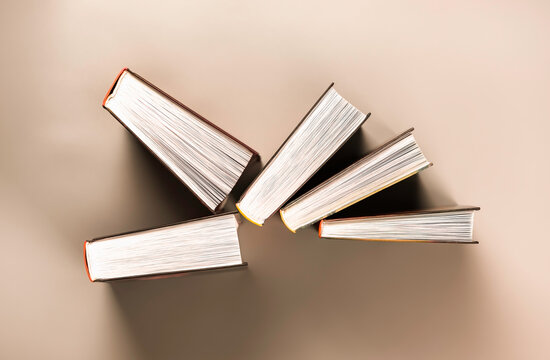 Group of books stands chaotically against red background.