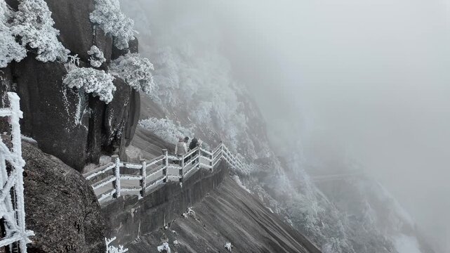 Huangshan, China: Panoramic footage of hiking trail by the steep cliff in the frozen Yellow mountain, Mt Huangshan in China during a cold a foggy winter day in Anhui province