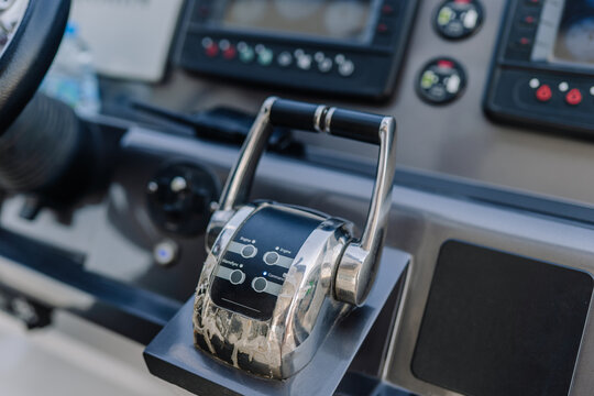 Boat throttle control lever with buttons and gauges in a modern marine dashboard, featuring a sleek design and metallic finish for navigation and operation