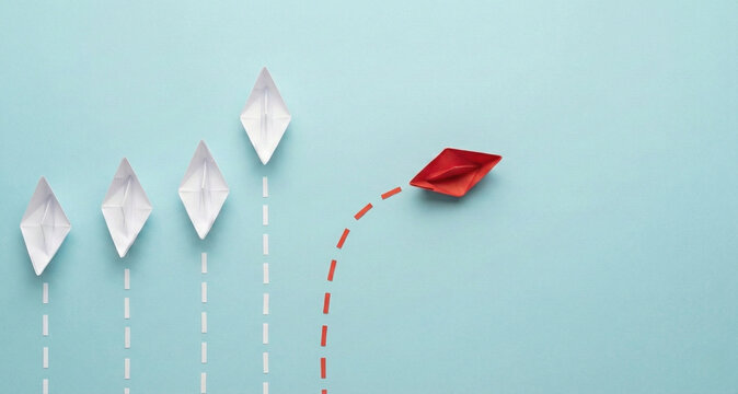 Red paper boat changing direction from white boats on blue background