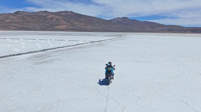 The motorbike rides past the salt mining area on Laguna Salinas, showing large square harvest plots with salt piled up and ready for collection by local workers.