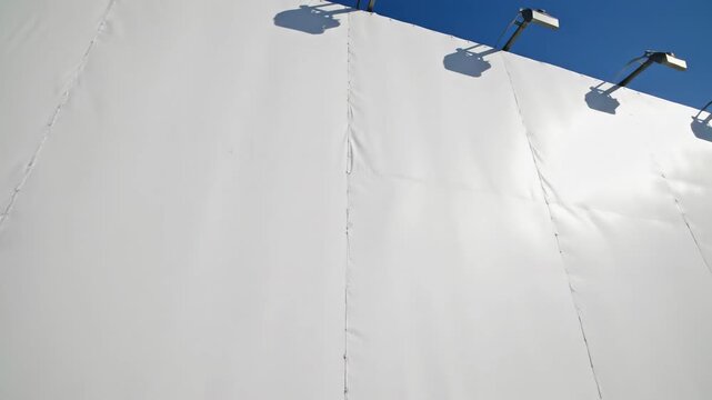 Impressive low angle view looking straight up at the towering support structure of a massive blank white vinyl advertisement panel soaring above the city streets development, massive, white