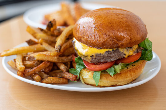 A cheeseburger with lettuce and tomato and fries on a white plate at a modern American restaurant