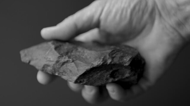Perfectly Preserved Paleolithic Biface Pick: Authentic Stone Age Hand Tool and Prehistoric Artifact (slow motion 4K). black and white video