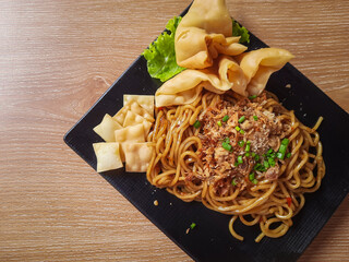 a plate of spicy Indonesian fried noodles or called mie goreng, served with crispy fried wontons.&nbsp;